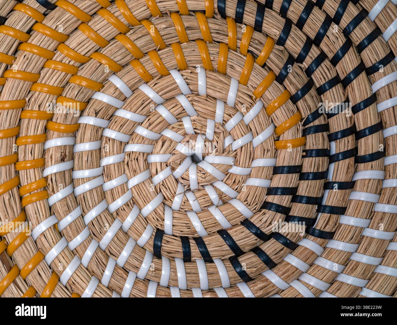 I motivi colorati nella texture circolare di un cesto in tessuto Foto Stock