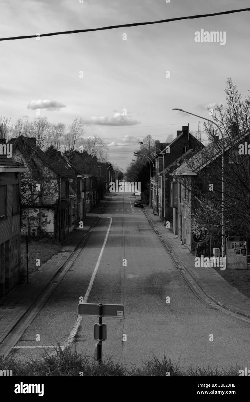 Strada abbandonata in un'area urbana desolata durante il giorno che mostra edifici vuoti e un cielo nuvoloso Foto Stock