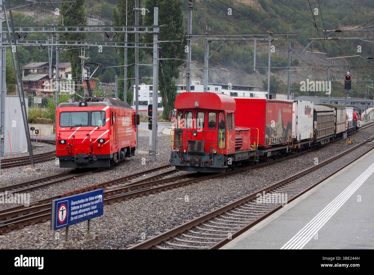 Matterhorn Gotthard Bahn GM 3/3 diesel shunter 71 arrivo a Visp con un carico per Zermatt dal deposito di trasferimento, posto elettrico in attesa a sinistra Foto Stock