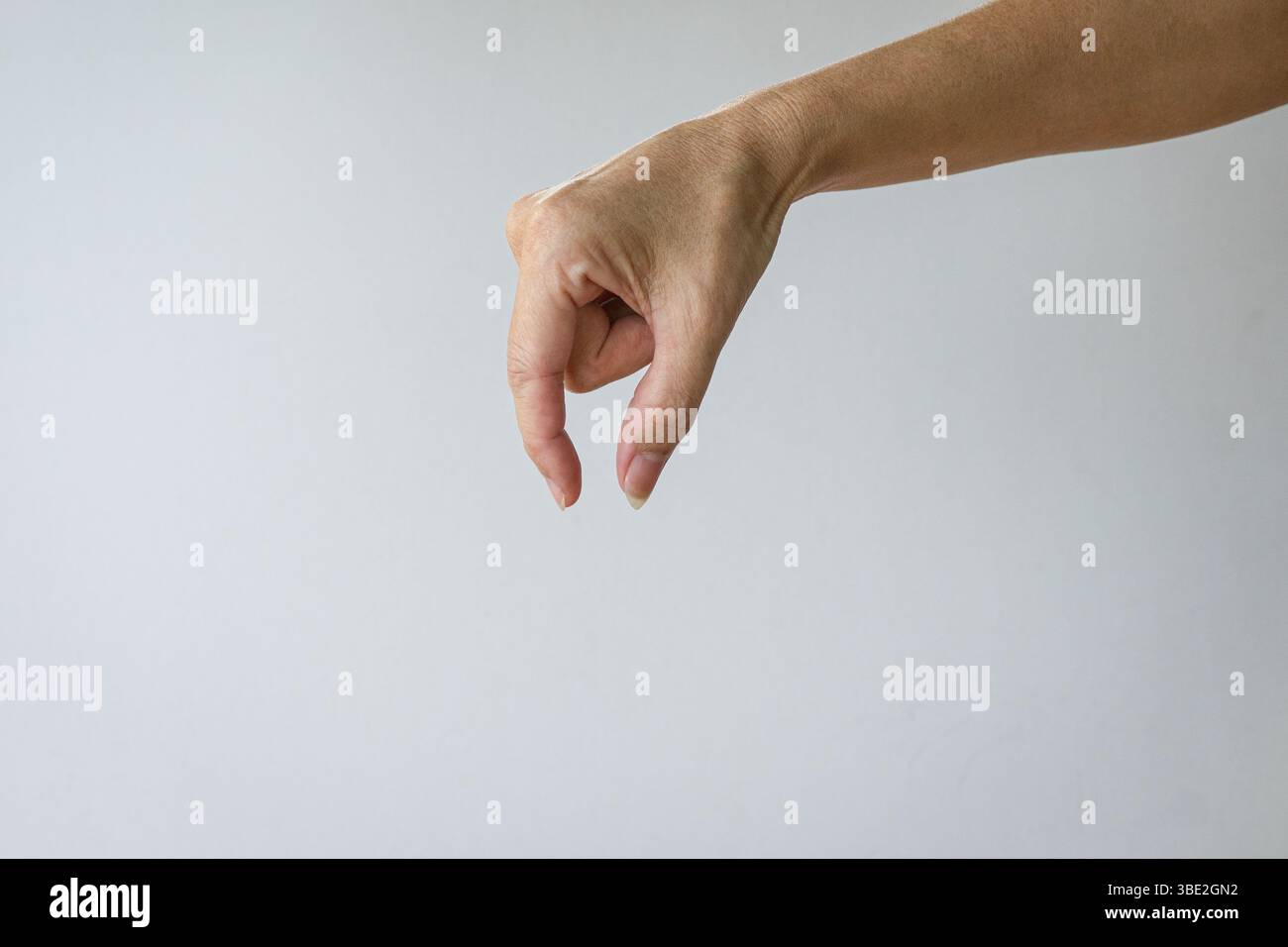 La mano femminile forma un gesto di raccogliere qualcosa di invisibile. Isolato su sfondo bianco. Foto Stock