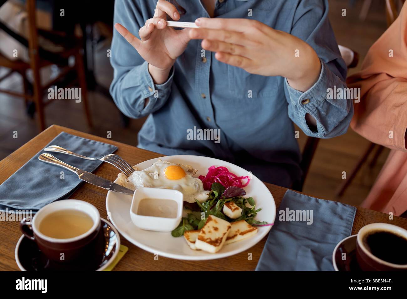 I giovani amici condividono una piacevole esperienza di brunch mentre catturano l'attimo sul telefono. Foto Stock