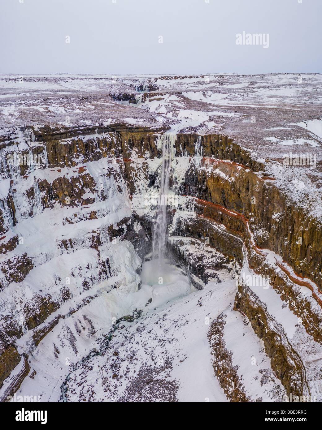 Vista aerea della cascata di Hengifoss ricoperta di neve nell'Islanda orientale in inverno. Foto Stock