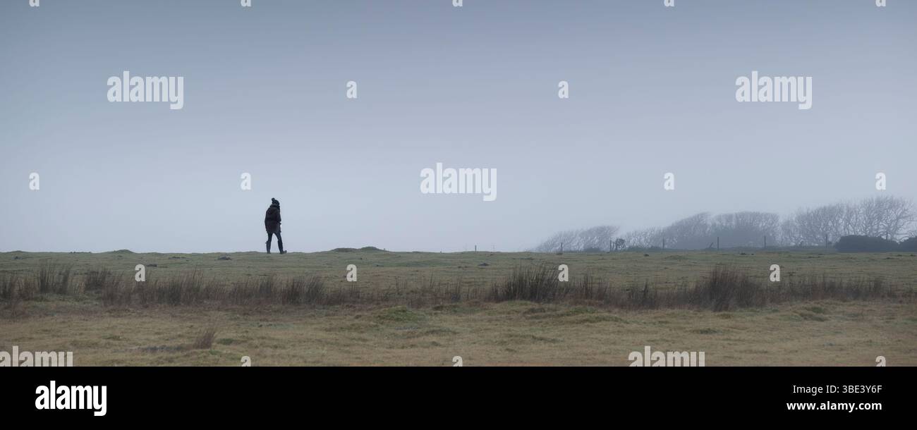 Un'immagine panoramica di una persona che cammina in condizioni meteorologiche nebbiose a Bodmin Moor in Cornovaglia nel Regno Unito. Foto Stock