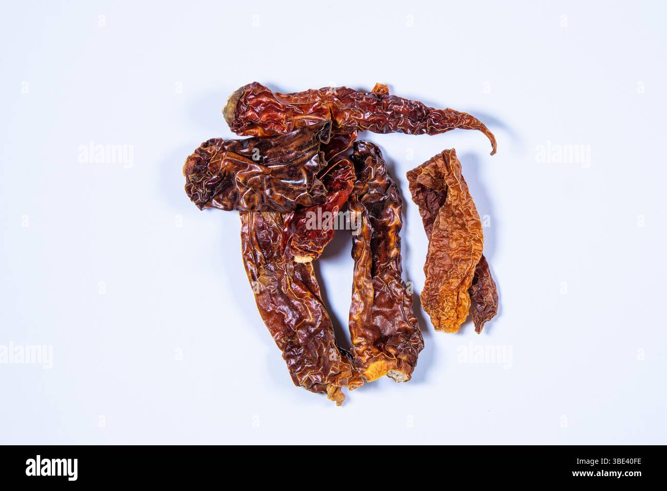 Peperoncini rossi Kashmiri secchi su uno sfondo bianco e pulito, evidenziando i loro colori vivaci e la consistenza rugosa, ideale per temi culinari. Foto Stock
