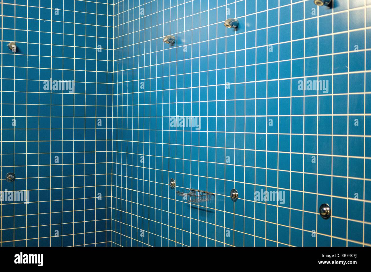 parete doccia piastrellata blu con ganci minimalisti in una palestra Foto Stock