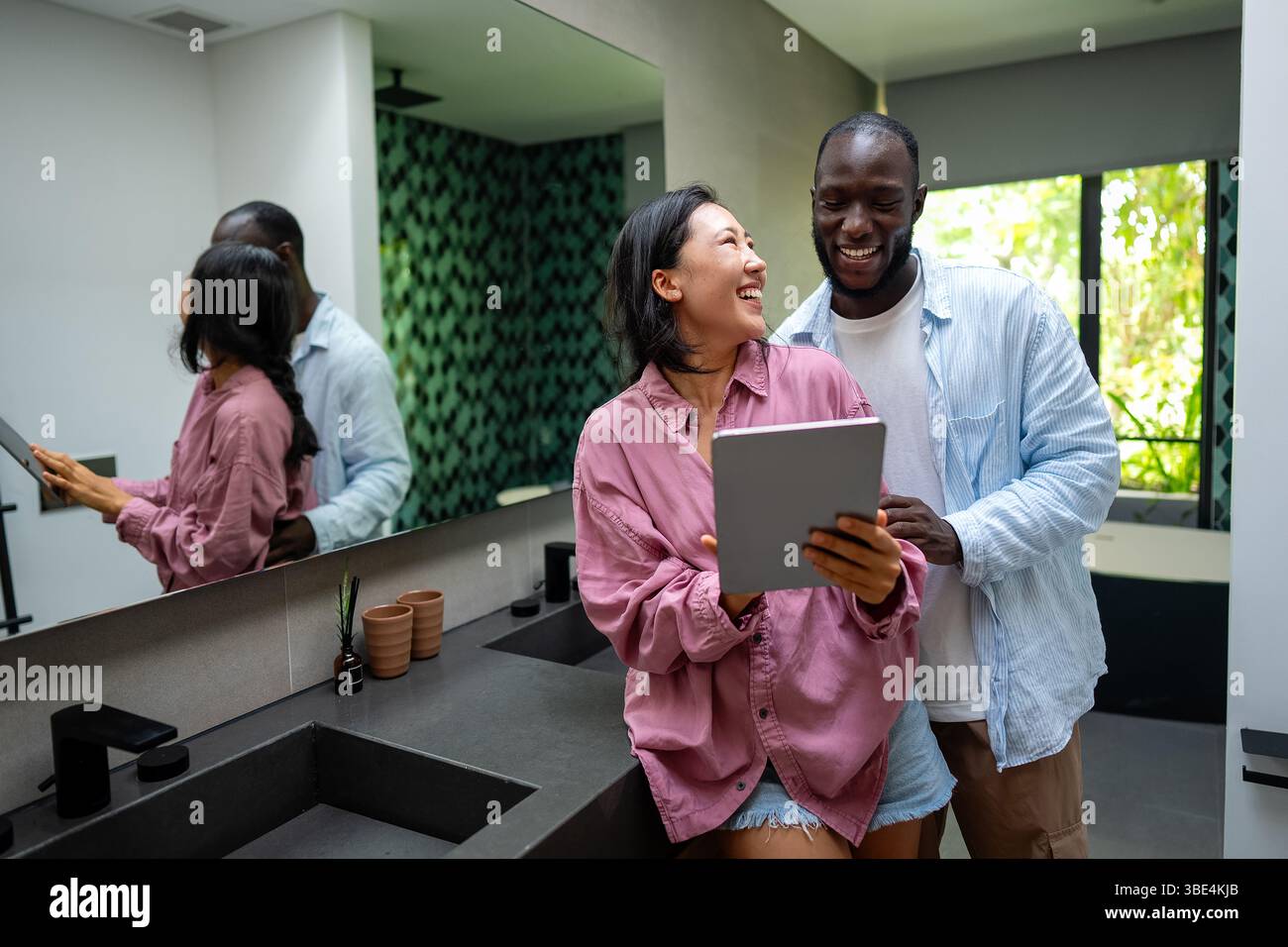 Felice coppia multietnica che utilizza un notebook, acquista online con le vendite, gioca insieme Foto Stock