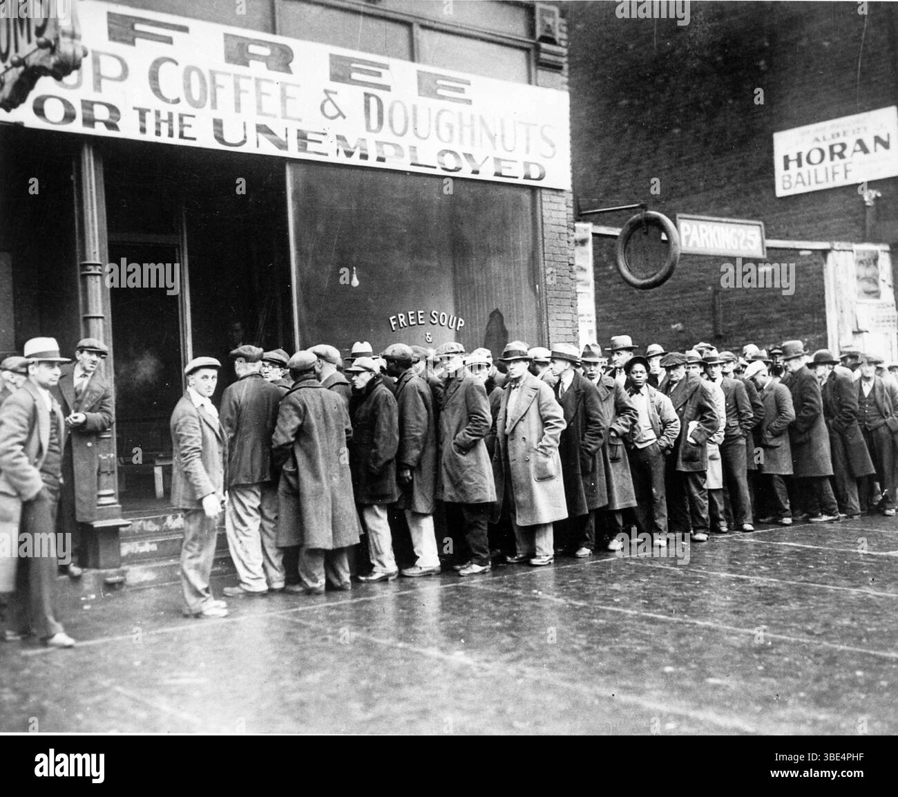 Una lunga fila di disoccupati aspetta fuori da una cucina di zuppe durante la grande depressione. Alphonse Gabriel Capone (17 gennaio 1899 – 25 gennaio 1947), a volte conosciuto con il soprannome di Scarface, è stato un gangster e uomo d'affari statunitense che ha raggiunto la notorietà durante l'era del proibizionismo come co-fondatore e capo del Chicago Outfit dal 1925 al 1931. Il suo regno di sette anni come boss del crimine finì quando fu imprigionato all'età di 33 anni. Foto Stock