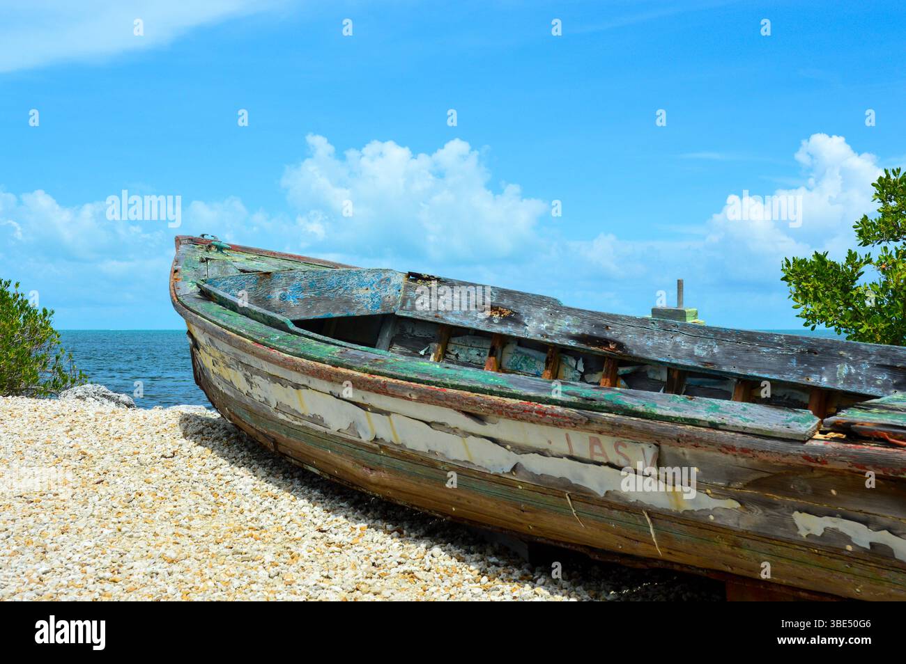 Una vecchia barca a remi seduta su ghiaia che si affaccia sull'oceano Foto Stock
