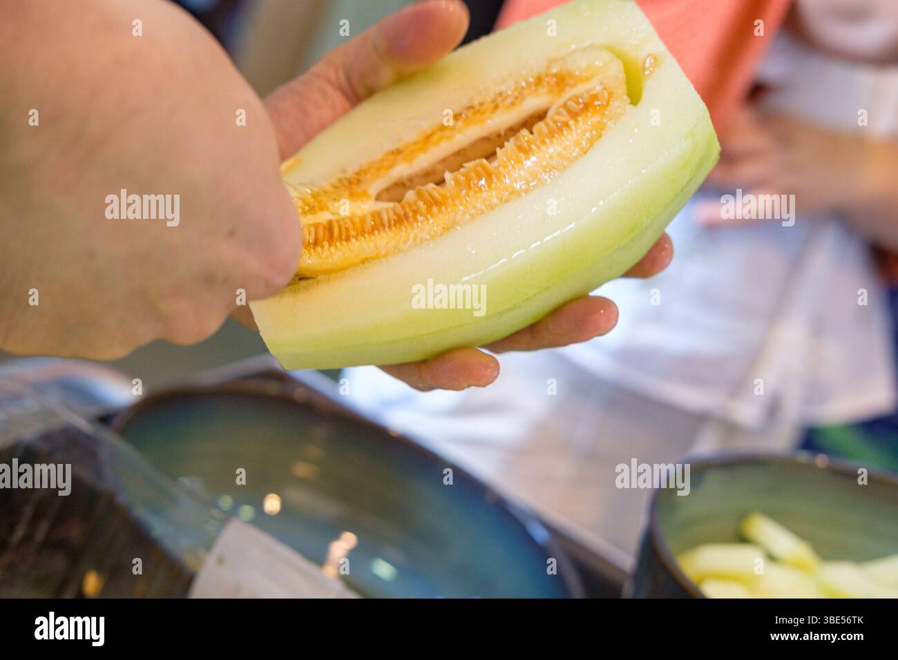raccogliere a mano i semi dal melone fresco di melone di melone con un cucchiaio Foto Stock