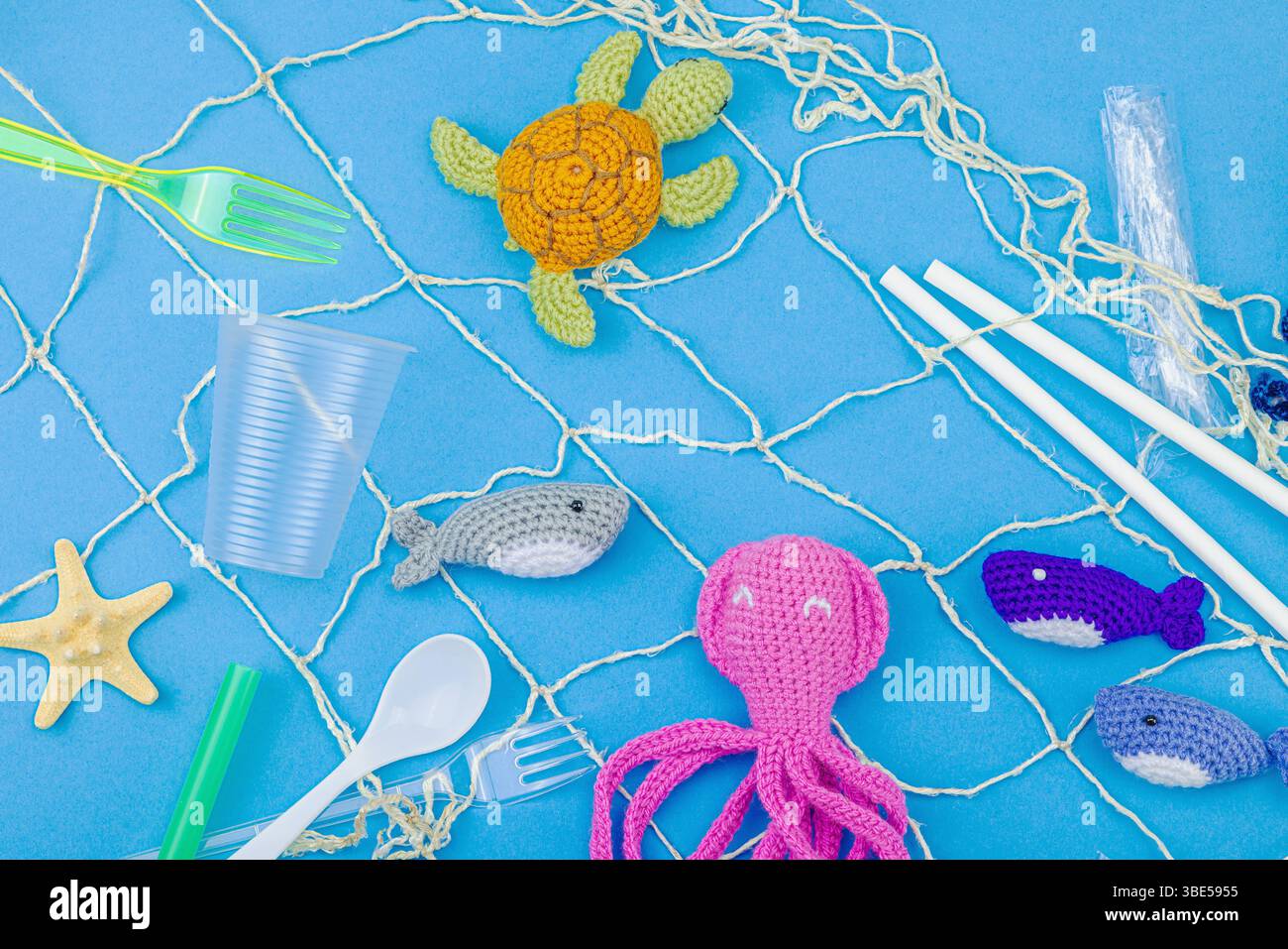 Giornata Mondiale degli oceani, consapevolezza dell'inquinamento idrico e immagini di educazione ambientale. Animali marini a uncinetto fatti a mano intrappolati in articoli di plastica monouso Foto Stock