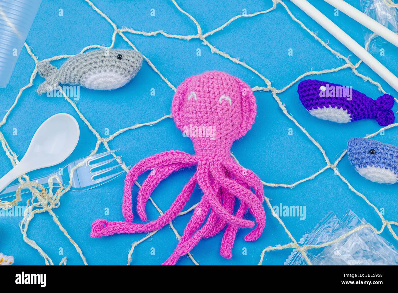 Giornata Mondiale degli oceani, consapevolezza dell'inquinamento idrico e immagini di educazione ambientale. Animali marini a uncinetto fatti a mano intrappolati in articoli di plastica monouso Foto Stock