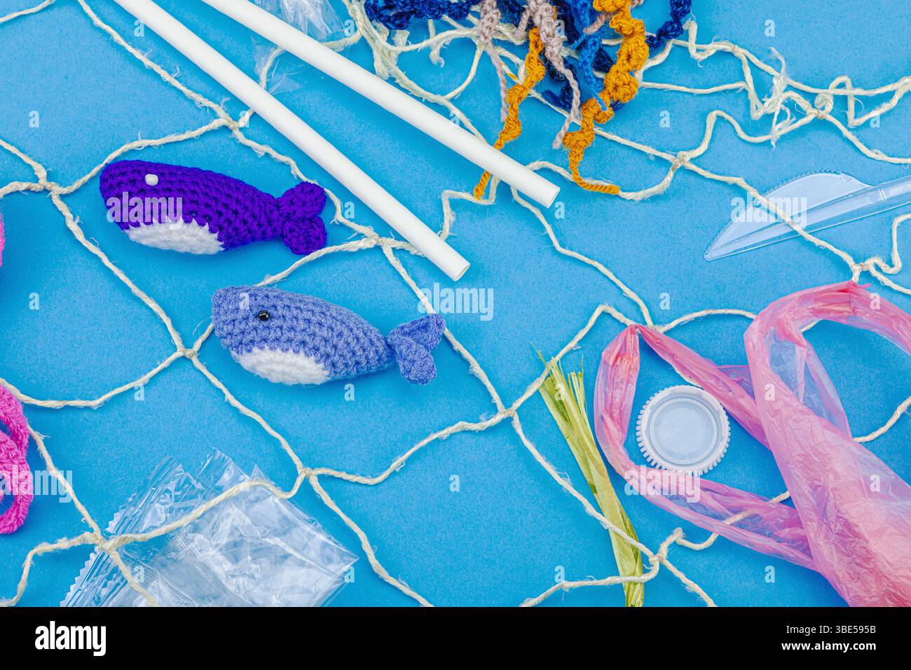 Giornata Mondiale degli oceani, consapevolezza dell'inquinamento idrico e immagini di educazione ambientale. Animali marini a uncinetto fatti a mano intrappolati in articoli di plastica monouso Foto Stock