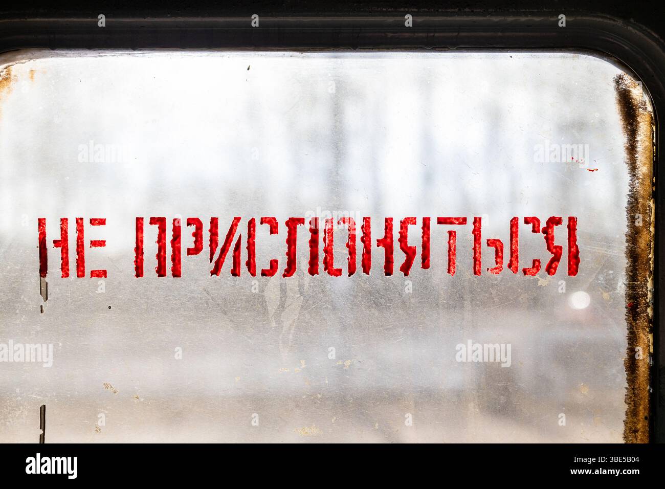 Vernice rossa non appoggiarsi contro il testo delle porte sul russo su vetro finestra della porta di trasporto del treno locale in soleggiata primavera sera Foto Stock