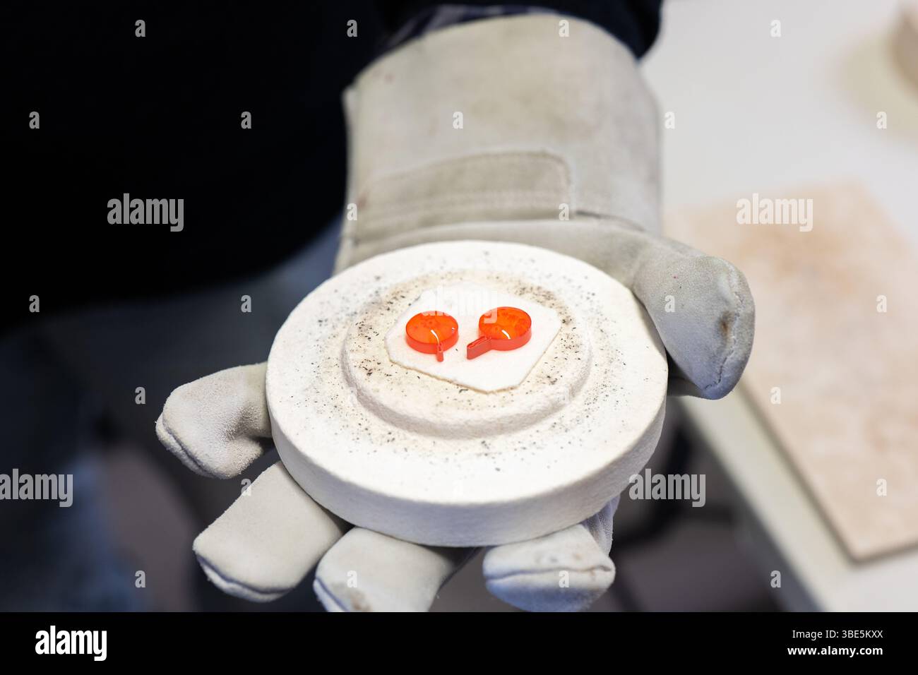 Primo piano della mano dei guanti di un artigiano che regge intricati pezzi di vetro di Burano e Murano provenienti da Venezia. Questi vivaci vetri realizzati a mano sono caratterizzati da tr Foto Stock