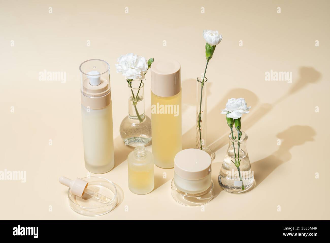 Un'esposizione completa di vari contenitori cosmetici con fiori bianchi in matracci e cilindri da laboratorio, che ritraggono un'estetica di bellezza pulita ed equilibrata in un'unica occasione Foto Stock