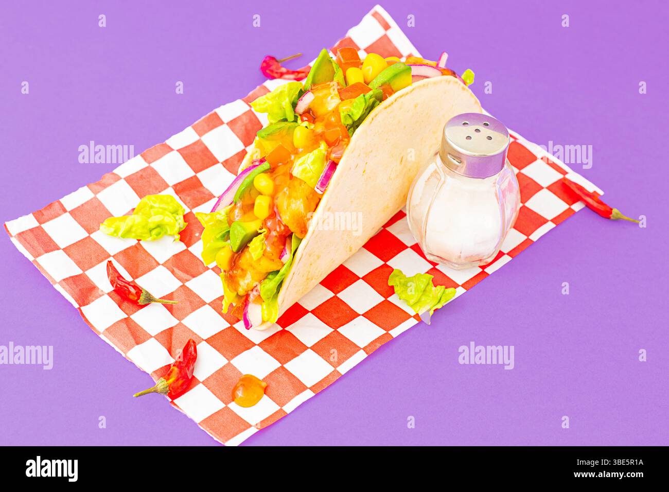 Dall'alto un colorato taco con gocce di salsa calda, peperoncino e lime. Riprese in studio con luce intensa e contrasto elevato Foto Stock