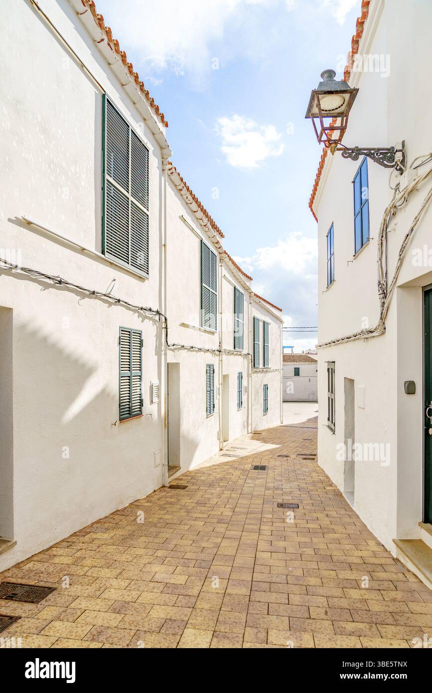Scena di strada con edifici imbiancati e tende verdi in Un affascinante villaggio mediterraneo a Minorca, Isole Baleari. Architettura tradizionale, Foto Stock