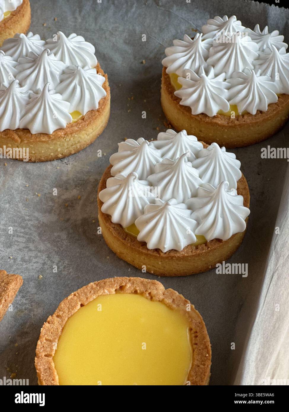 Preparazione di una classica tarte aux citrons francese, crosta di pasta sfoglia ripiena di scorza di limone e condita con una delicata meringa Foto Stock