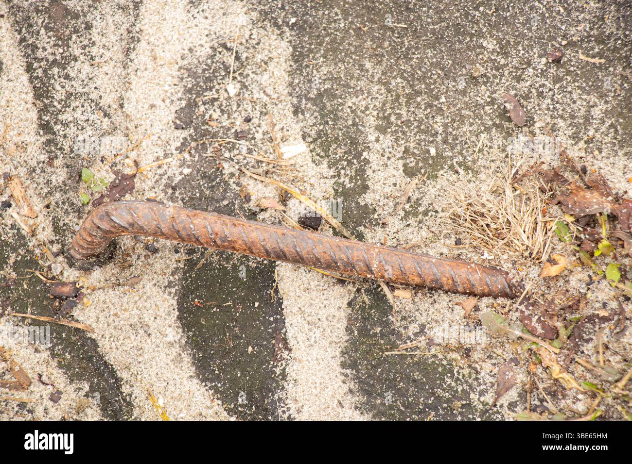 Rinforzo in metallo arrugginito che fuoriesce dal terreno in un cantiere, area pericolosa Foto Stock