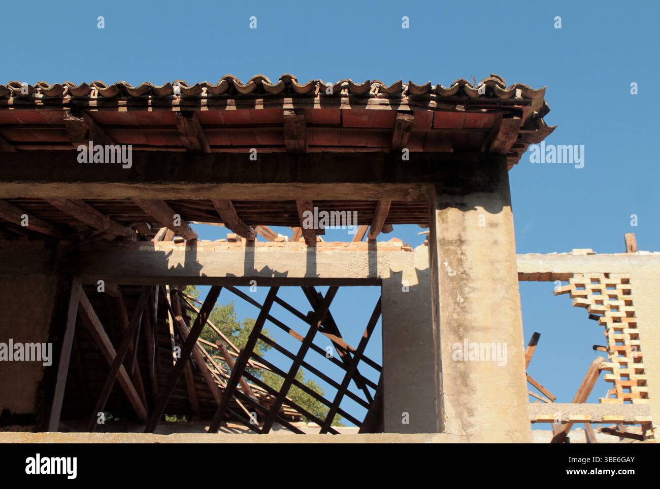 Travi di legno crollate all'interno di una vecchia rovina abbandonata di una fattoria, rivelando il cielo attraverso quello che una volta era il tetto. Anche le pareti sono danneggiate, crollano. Foto Stock