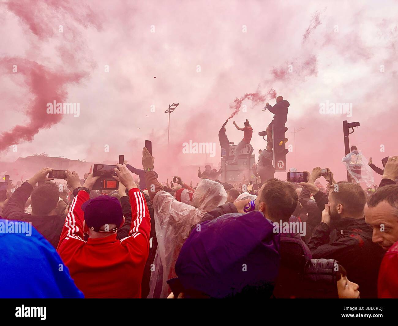 I fan girano la parata del Liverpool FC mentre la folla si riunisce a Strand Street, Liverpool, Regno Unito, prima dell'arrivo dell'autobus scoperto della squadra. 26 maggio 2025. - Immagine stock catturata con smartphone