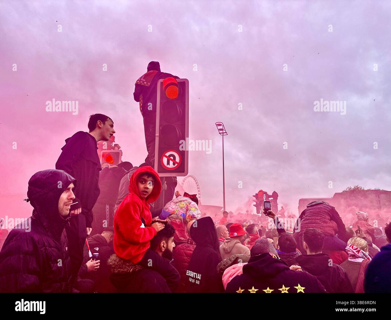 I tifosi aspettano l'autobus di Liverpool durante la parata della vittoria, alcuni sui semafori e sulle spalle, Strand Street, Liverpool, Regno Unito. Lunedì, 26 maggio 2025. Foto Stock