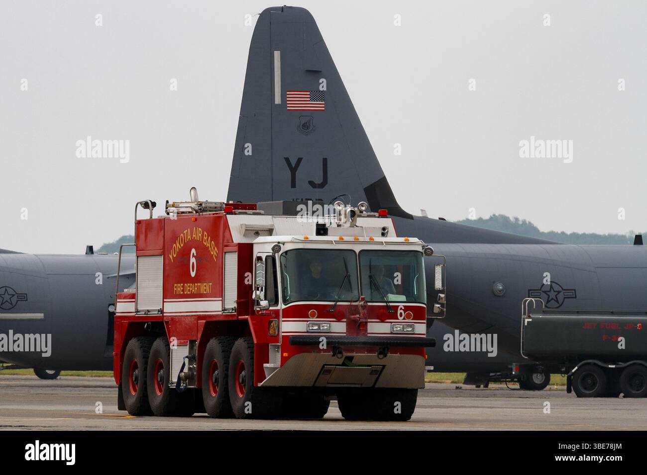 Un camion di soccorso e antincendio P23 con l'USAF a Yokota, base aerea di fronte all'aereo parcheggiato C130J Super Hercules, Tokyo, Giappone. Foto Stock