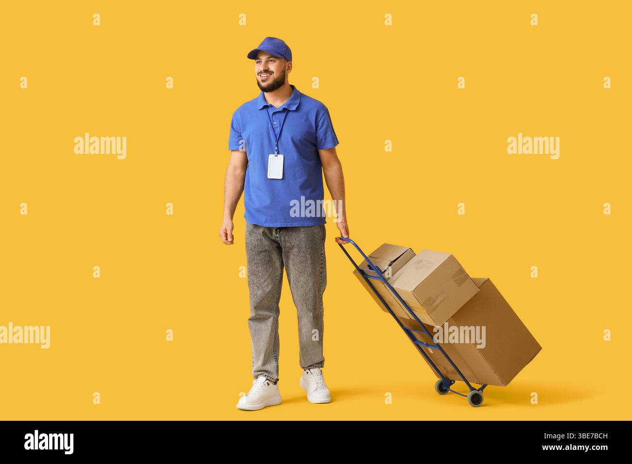 Carrello per corriere maschio con scatole per pacchi su sfondo giallo Foto Stock