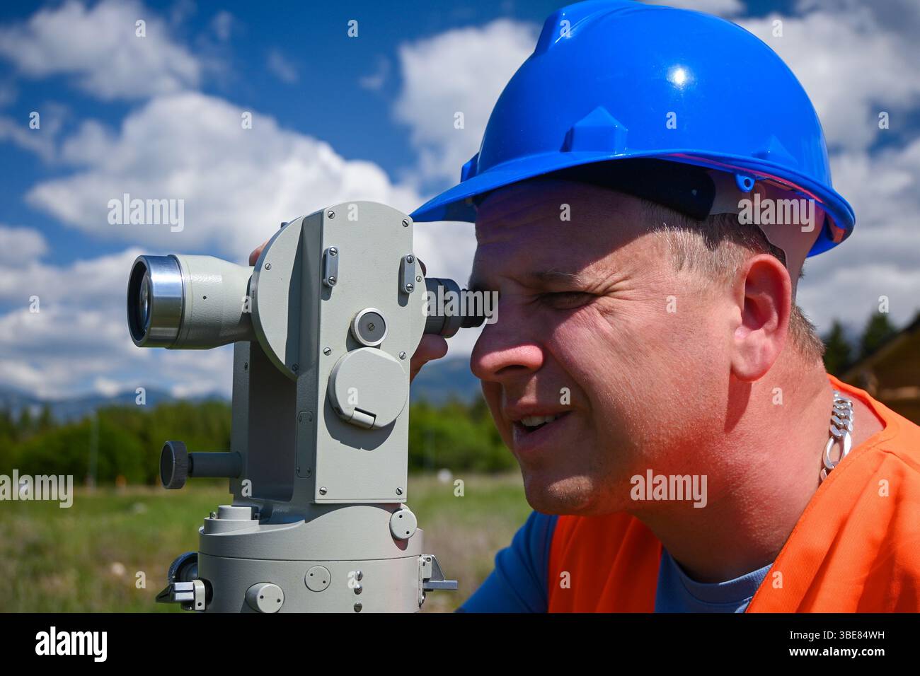 Surveyor che lavora con apparecchiature per il trasporto di teodolite in cantiere all'aperto durante i lavori di rilevamento. Foto Stock