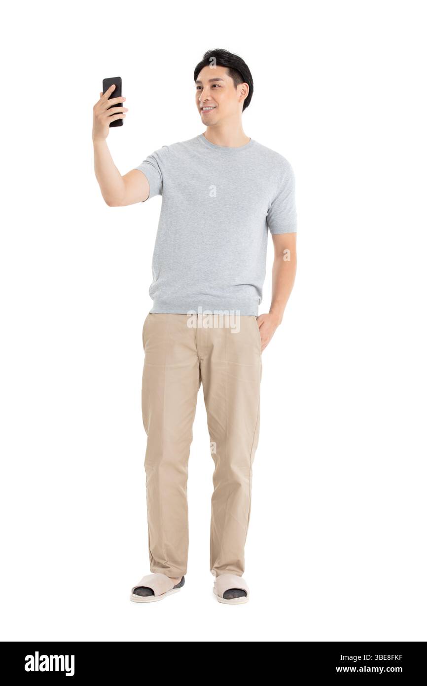 Un giovane che fissa il suo schermo del telefono, assolutamente entusiasta con il braccio alzato in alto Foto Stock