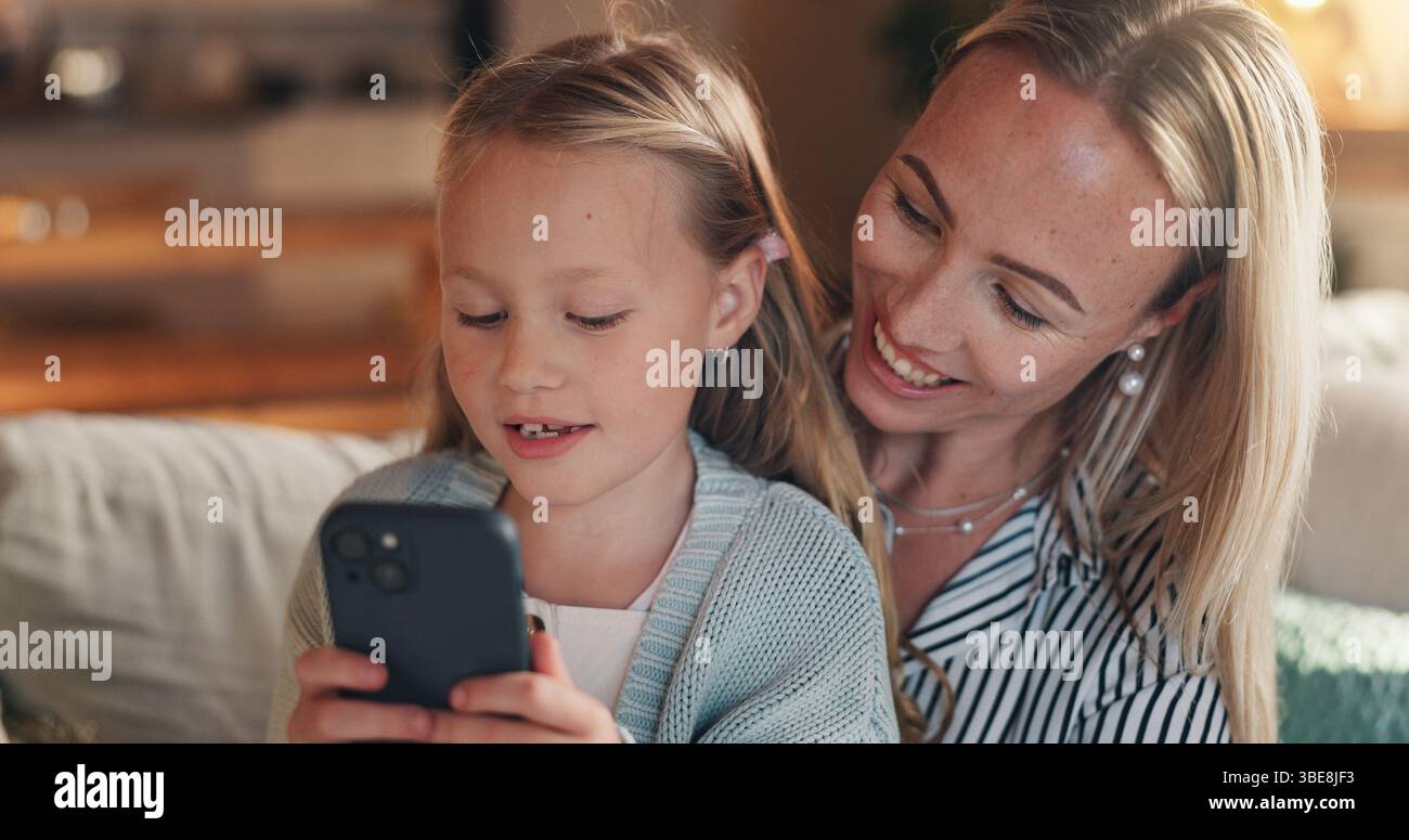 Casa, madre e ragazza con smartphone, sorridere e legare insieme all'intrattenimento online. Famiglia felice, cellulare e genitore sul divano, mamma o. Foto Stock
