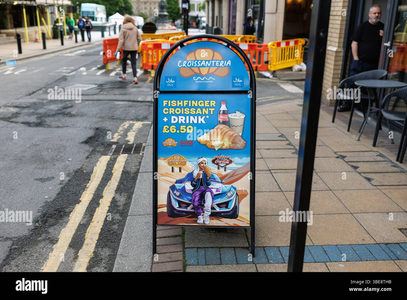 Un cartello che pubblicizza la Croissanteria su Division Street, Sheffield, Regno Unito, il 26 maggio 2025. Il cartello sul marciapiede promuove un'offerta di bibite e croissant a dito di pesce al prezzo di £ 6,50 e presenta un'opera d'arte IA di bassa qualità di una donna che mangia un grande croissant nel deserto. Cattiva pubblicità ai, cattiva arte ai, A-board, tabellone pubblicitario, cartellone per negozi di strada Foto Stock Un cartello che pubblicizza la Croissanteria su Division Street, Sheffield, Regno Unito, il 26 maggio 2025. Il cartello sul marciapiede promuove un'offerta di bibite e croissant a dito di pesce al prezzo di £ 6,50 e presenta un'opera d'arte IA di bassa qualità di una donna che mangia un grande croissant nel deserto. Cattiva pubblicità ai, cattiva arte ai, A-board, tabellone pubblicitario, cartellone per negozi di strada Foto Stock
