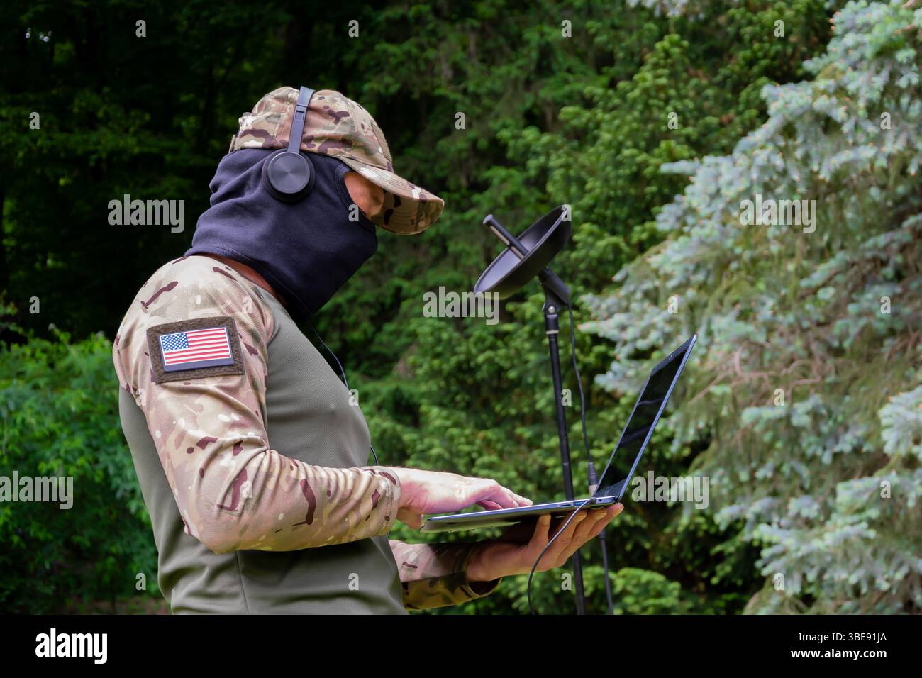 Un soldato che indossa una balaclava e le cuffie cattura i segnali acustici sul campo Foto Stock