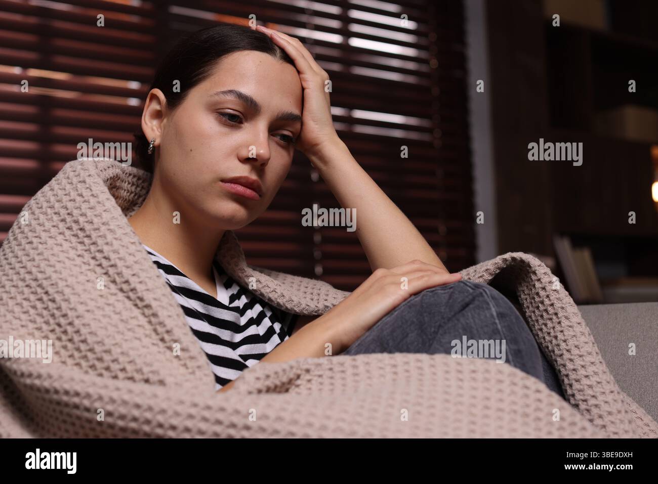 Donna depressa avvolta in plaid a casa Foto Stock