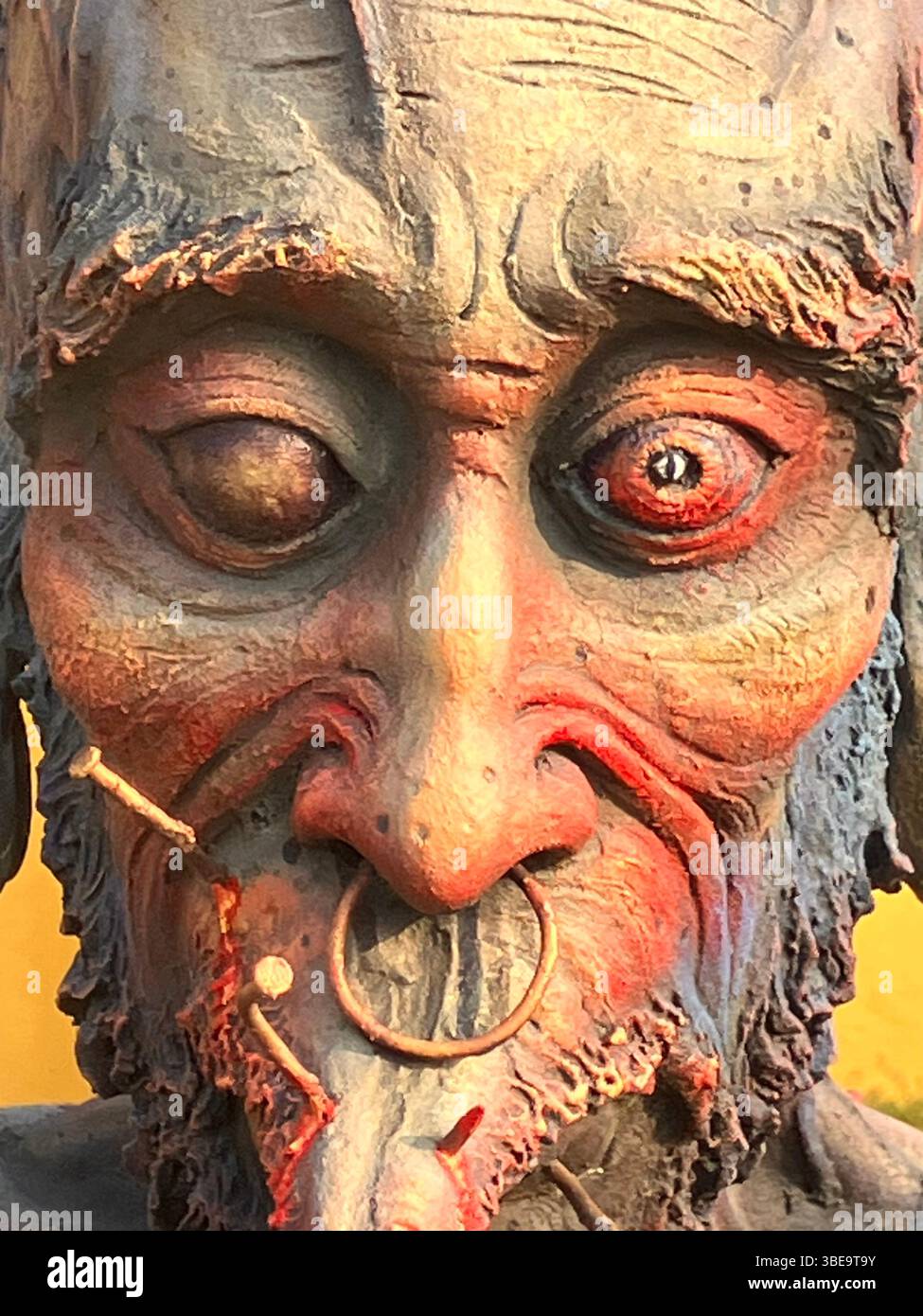 Primo piano di una scultura espressiva in un tempio buddista in Thailandia, catturando intense emozioni attraverso un volto di dolore, rabbia e sofferenza. Foto Stock