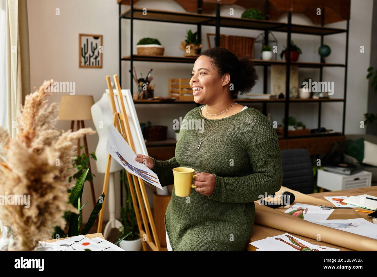 In un vivace laboratorio di artigianato, una donna si rilassa con una bevanda calda in mano, realizzando disegni. Foto Stock