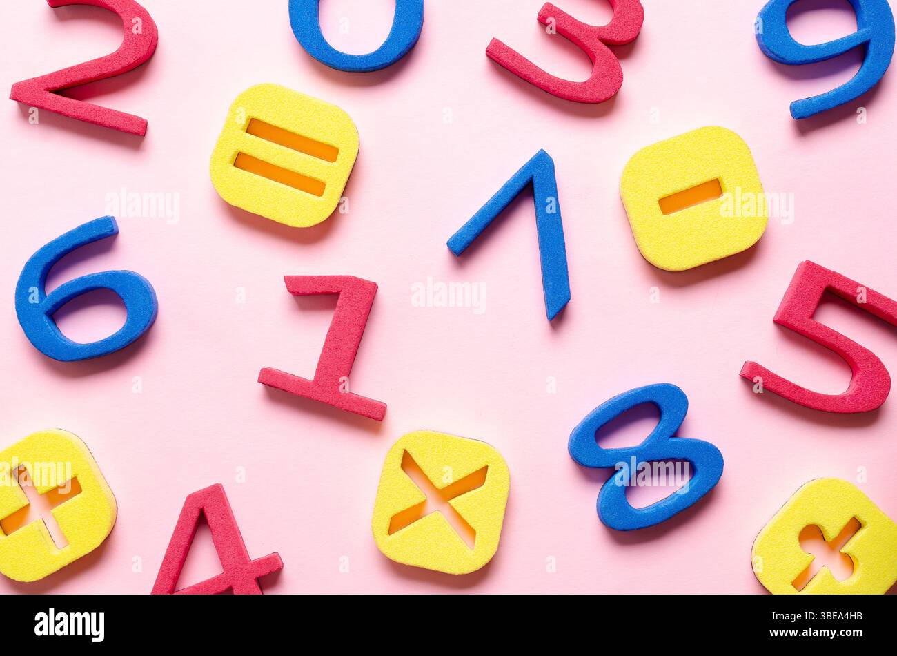Numeri di schiuma colorati e simboli matematici su sfondo rosa. Foto Stock