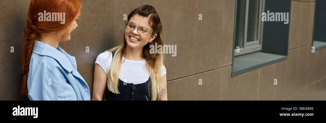 Due giovani donne si impegnano in una conversazione vivace, godendosi compagnia a vicenda, striscione Foto Stock