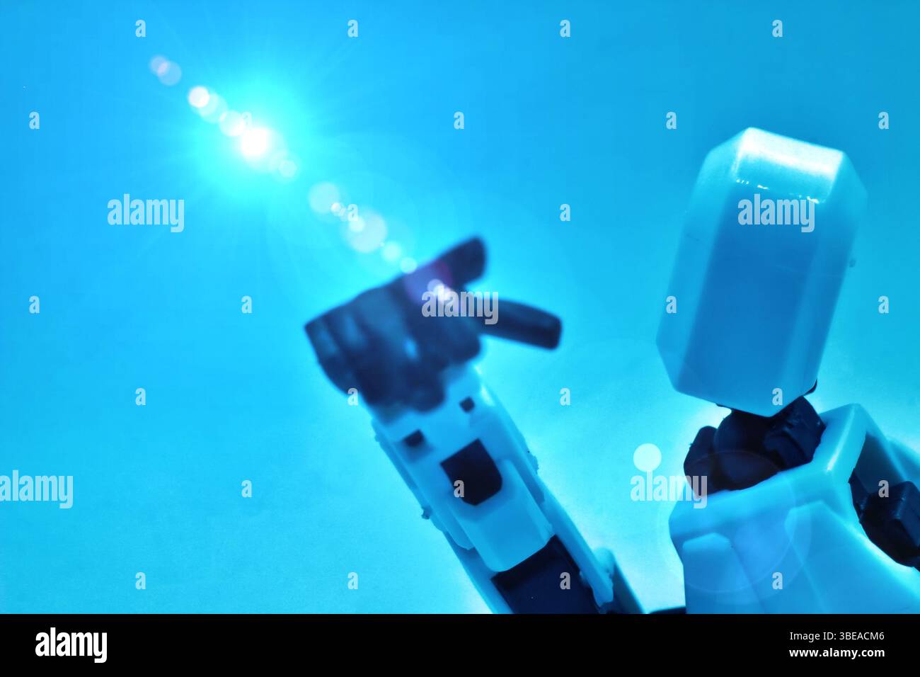 robot umanoide che mostra mano e futuristico con le persone sfocate sullo sfondo Foto Stock