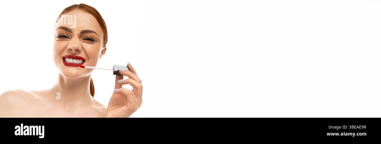 Una giovane donna esalta la sua bellezza applicando il rossetto rosso in uno spazio ben illuminato ed elegante. Foto Stock