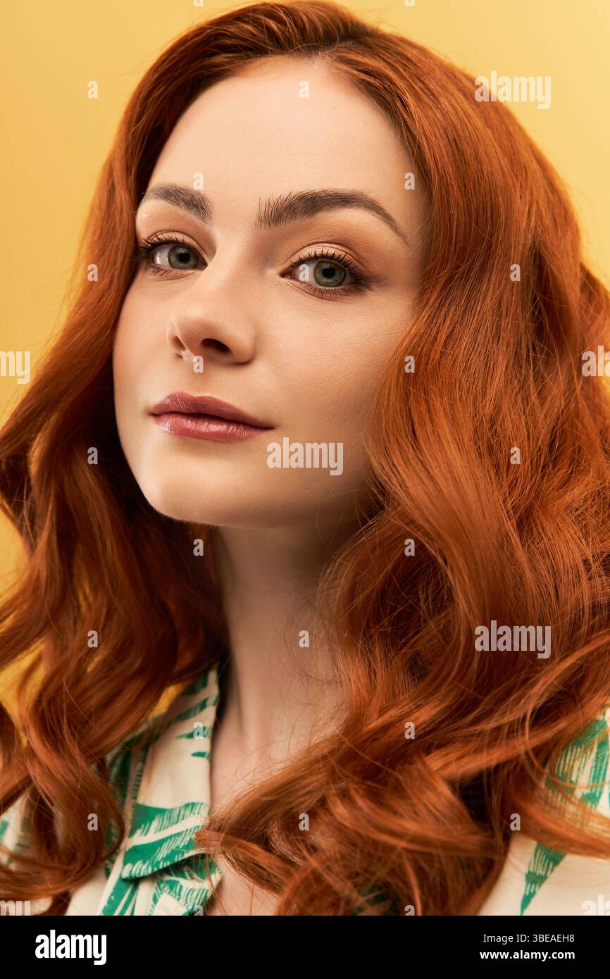 Giovane donna radiosa con ricci rossi che sfoggiano la sua bellezza e la sua fiducia in un ambiente vivace. Foto Stock