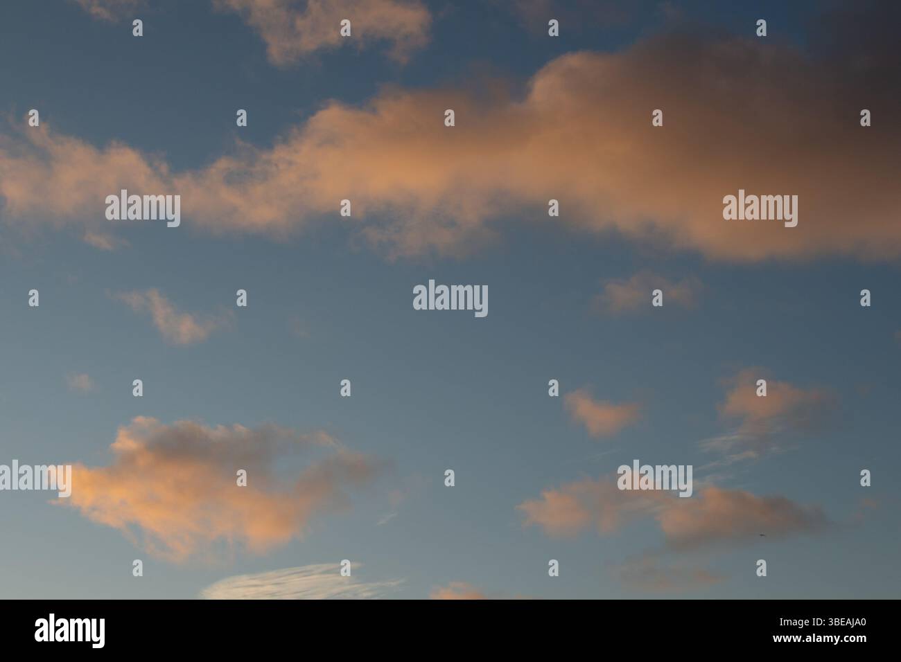 Captura un instante de serena belleza donde el cielo se convierte en un lienzo vibrante al atardecer. Las nubes, teñidas con suaves matices de durazno Foto Stock