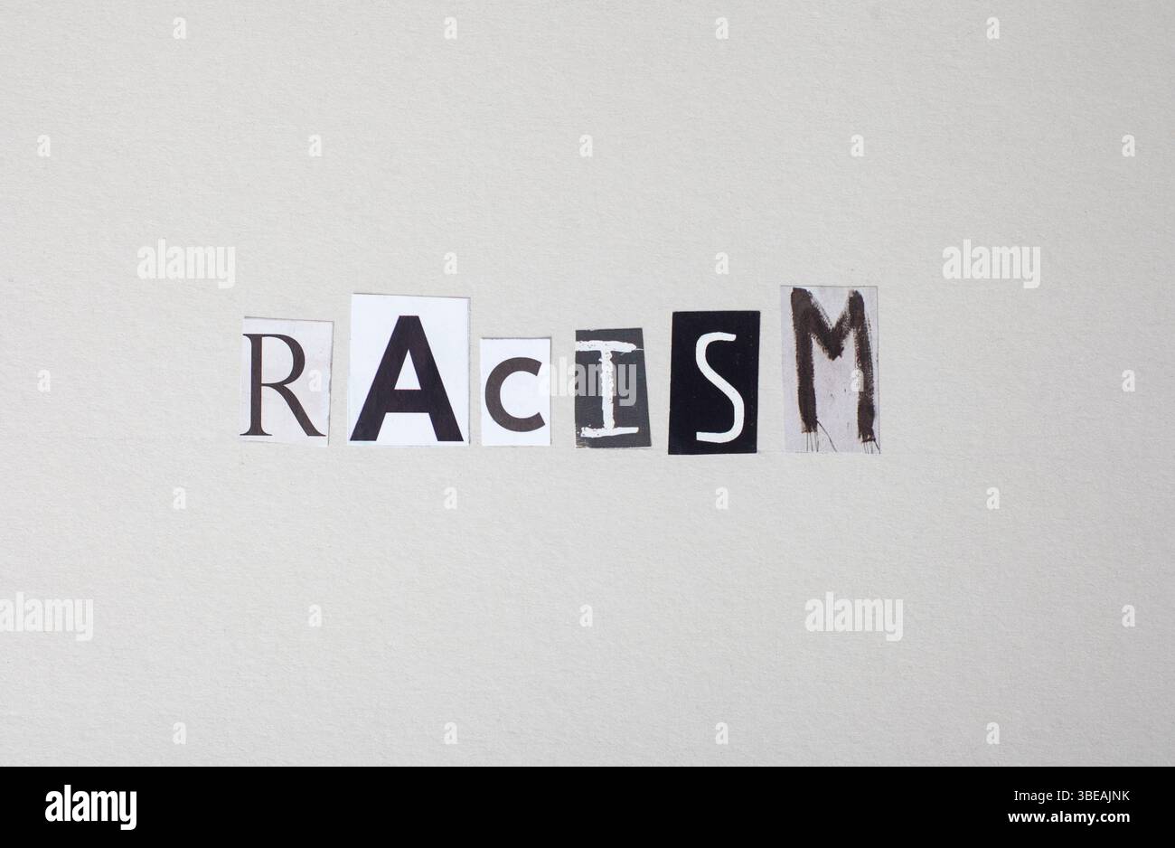 La parola razzismo è scritta in lettere di riviste in grigio chiaro. È una parola che viene spesso usata per descrivere il trattamento ingiusto delle persone basate su di te Foto Stock