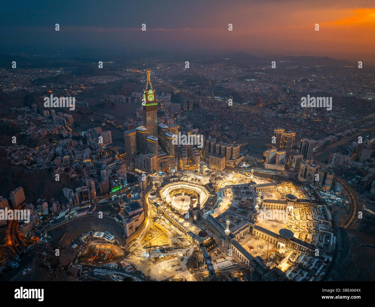 Vista aerea di notte della grande Moschea illuminata e della Torre dell'orologio Abraj al-Bait a la Mecca, che mostra il vibrante bagliore della città mentre le luci brillano acro Foto Stock