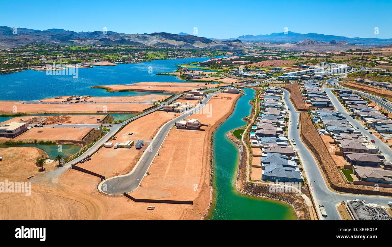Il sito di costruzione di Aerial Suburban Homes vicino a Lake and Mountains Fly Over Foto Stock
