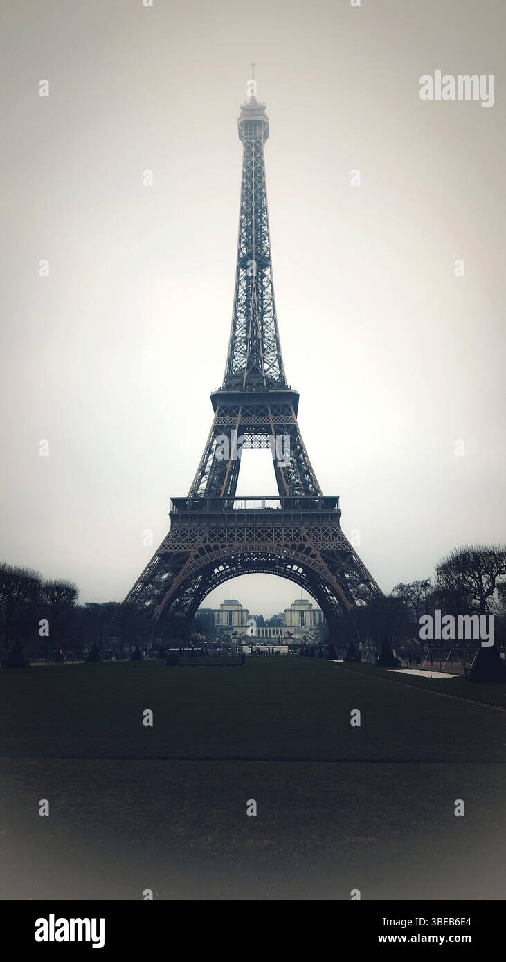 La Torre Eiffel si erge su di un cielo grigio a Parigi, circondata da giardini paesaggistici. Francia Foto Stock