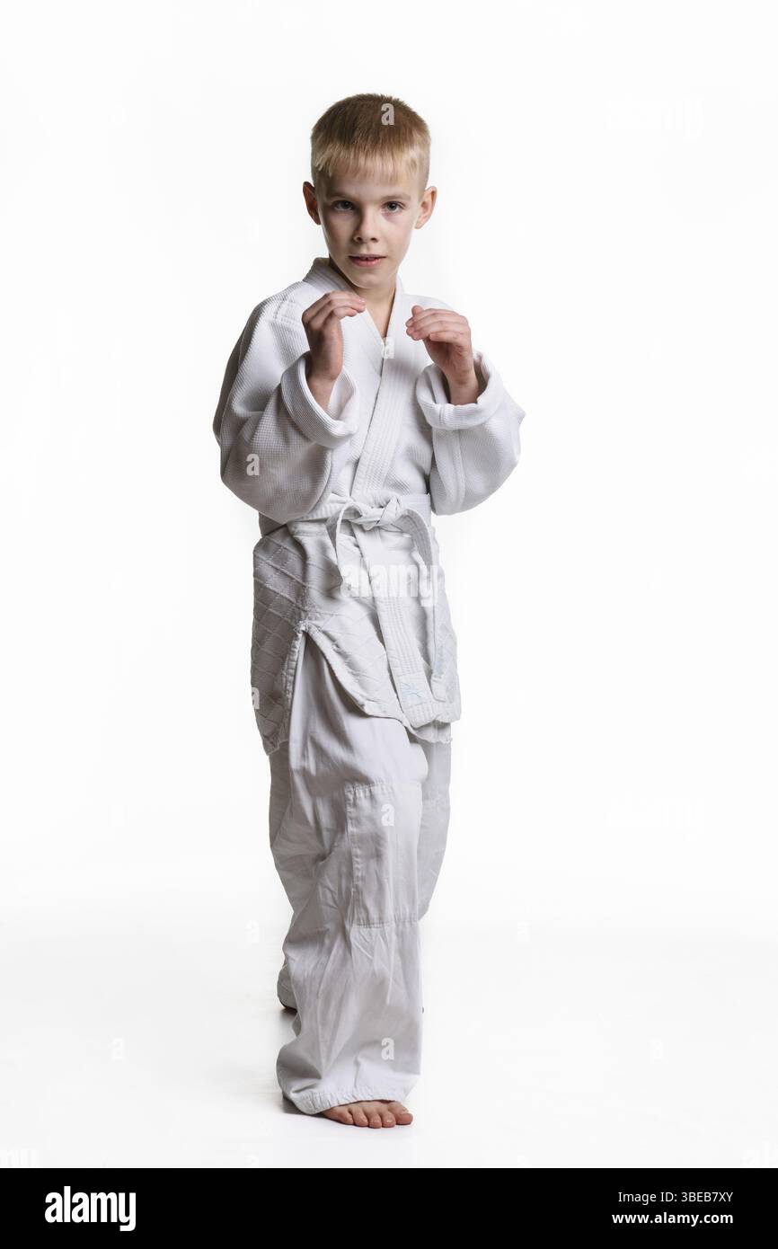 Un ragazzo si trova in una rastrelliera, studiando arti marziali Foto Stock