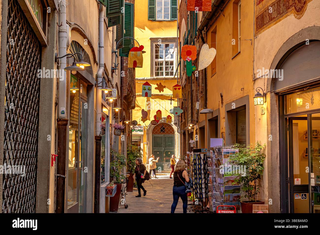 La gente camminava lungo Chiasso Barletti, una stradina stretta di Lucca, Italia Foto Stock