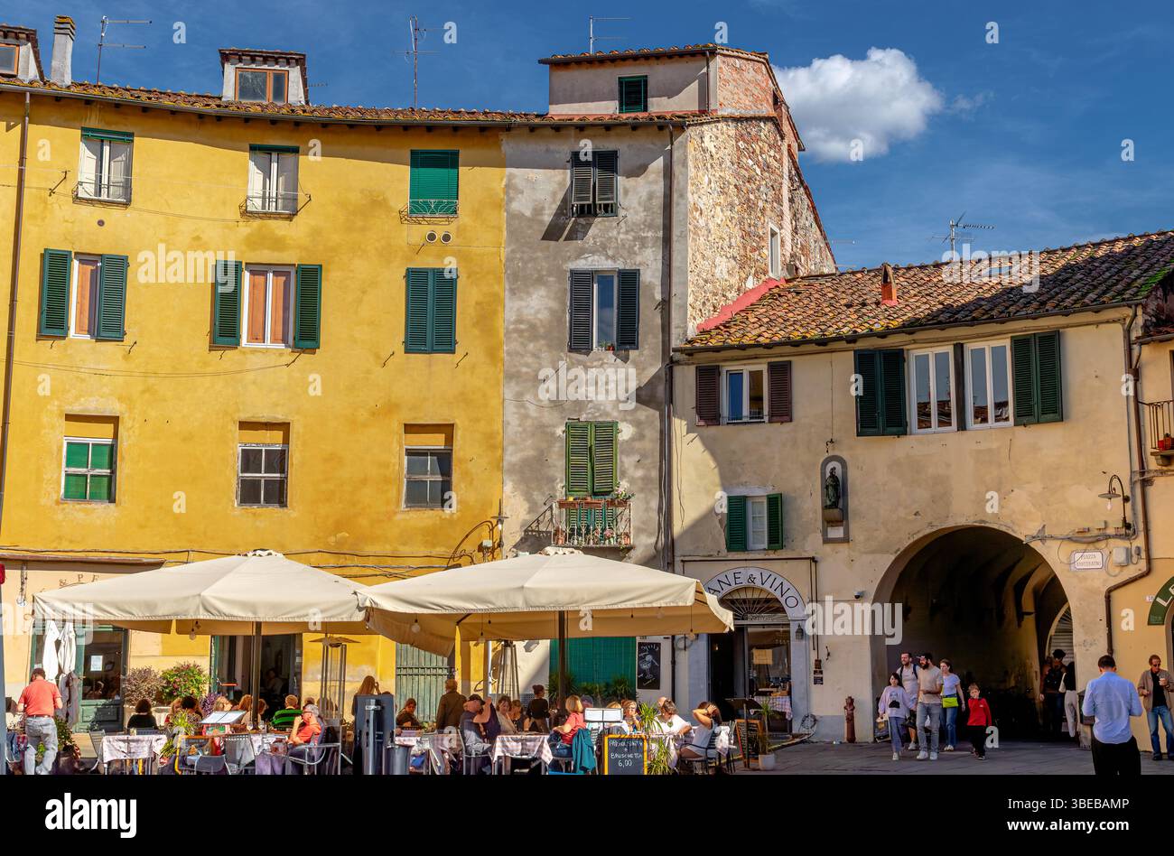 La gente cenava fuori in un ristorante in Piazza dell'Anfiteatro, una grande piazza circolare a Lucca, Italia Foto Stock