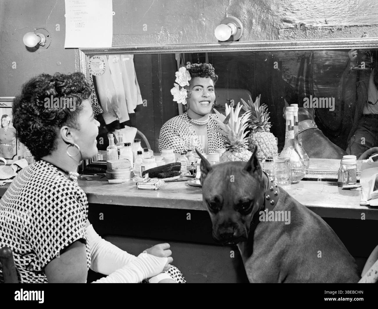 Billie Holiday e il suo cane Mister nello spogliatoio del Club Downbeat a febbraio 1947. Billie Holiday, nata Eleanora Fagan (New York, 7 aprile 1915 – New York, 17 luglio 1959), è stata una cantante statunitense di musica jazz e swing. Soprannominata "Lady Day" dalla sua amica e partner musicale, Lester Young, Holiday ha dato un contributo significativo alla musica jazz e al canto pop. Il suo stile vocale, fortemente influenzato dagli strumentisti jazz, ha ispirato un nuovo modo di manipolare il fraseggio e il tempo. Holiday era nota per le sue doti vocali e improvvisative Foto Stock
